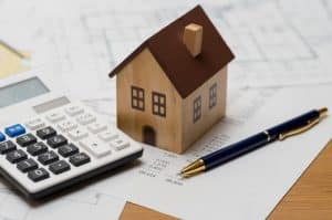 A homeowner with a laptop,and some paperwork calculates closing costs before a home sale.