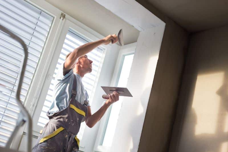 A man is applying paste to a valance to prepare it for a coat of paint. 